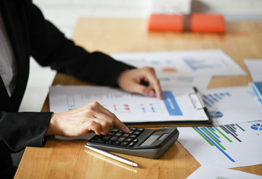 Reviewing business finances with a calculator to plan a debt restructuring